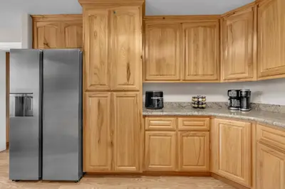 a kitchen with wooden cabinets and a stainless steel refrigerator at Prasad Retreat - Sunny Home with Deck & Air Hockey home in Arnold