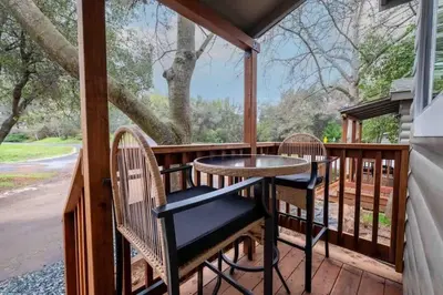 a porch with a table and chairs and a tree at Columbia Cabins Cabin 3 in Sonora