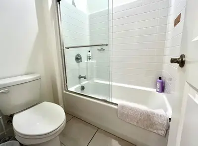 a white bathroom with a toilet and a shower at Spacious, bright and cozy space
