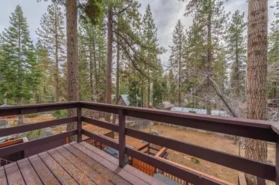 a wooden deck with trees in the background at Lakeside Serenity Retreat in Kings Beach