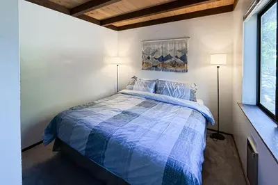 a bedroom with a bed with a blue comforter and two lamps at Vernal Vista in Yosemite West