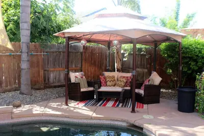 a gazebo with chairs and a table next to a pool at Luxurious 5-Bedroom Retreat with Saltwater Pool and Spa in Elk Grove