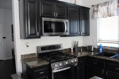 a kitchen with black cabinets and a stove and microwave at Luxurious 5-Bedroom Retreat with Saltwater Pool and Spa in Elk Grove