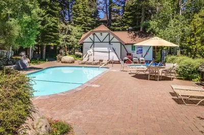 a swimming pool with a table and an umbrella at Tavern 16 in Olympic Valley