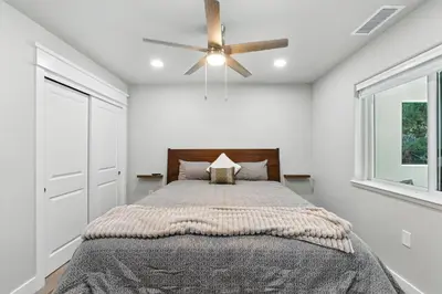 a bedroom with a bed with a ceiling fan at The White House Coveted Triplex Near Lake