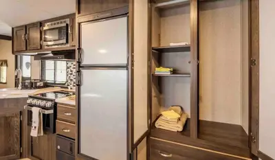 a kitchen with a refrigerator and a microwave at Parked RV Travel Trailer Getaway Wi-Fi with Hookups in Fresno