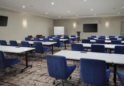 a conference room with tables and chairs and a screen at Hilton Garden Inn Merced in Merced