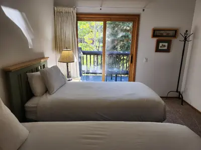 a bedroom with two beds and a door to a balcony at Snowcreek Resort Vacation Rental 934 in Mammoth Lakes