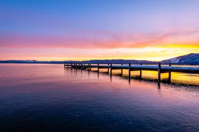 a pier on the water with a sunset in the background at Everline Resort & Spa 317 in Olympic Valley
