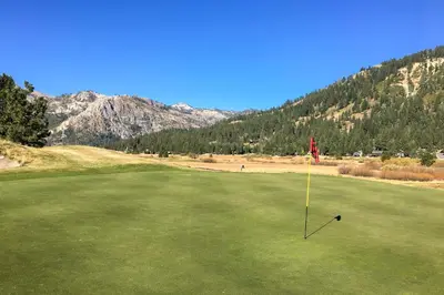 a golf club on a green with mountains in the background at Everline Resort & Spa 317 in Olympic Valley