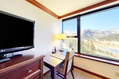 a room with a desk with a television and a large window at Everline Resort & Spa 810 in Olympic Valley