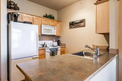 a kitchen with a white refrigerator and a sink at Sunstone # 329 in Mammoth Lakes