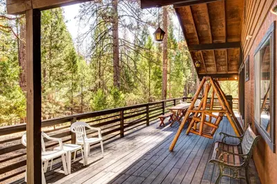 a porch of a cabin with chairs and a swing at 42A Megan in North Wawona