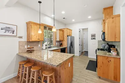 a kitchen with wooden cabinets and a island with bar stools at Leisure Landing Unwind in the Pines in Shaver Lake