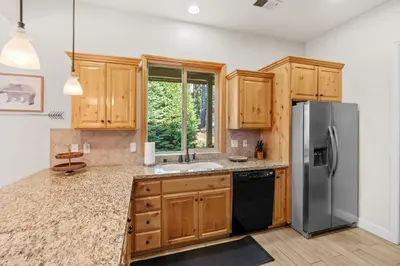 a kitchen with wooden cabinets and a stainless steel refrigerator at Leisure Landing Unwind in the Pines in Shaver Lake