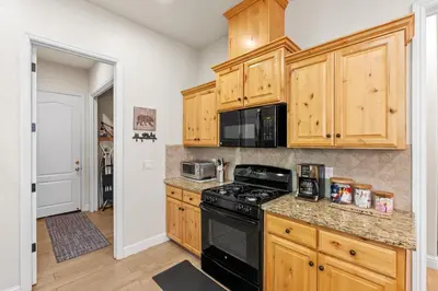 a kitchen with wooden cabinets and a black stove top oven at Leisure Landing Unwind in the Pines in Shaver Lake