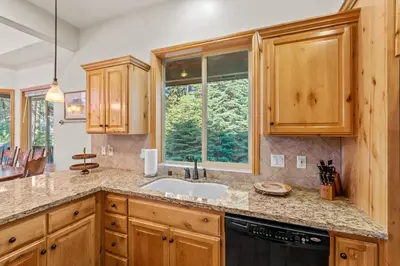 a kitchen with wooden cabinets and a sink and a window at Leisure Landing Unwind in the Pines in Shaver Lake