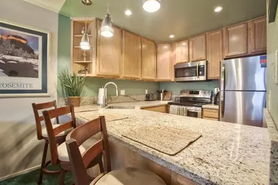 a kitchen with wooden cabinets and a granite counter top at Renovated Mountain Getaway, AC, Spa, Pool, Full Kitchen in Mammoth Lakes