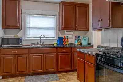 a kitchen with wooden cabinets and a sink and a microwave at 2BR Family Getaway with Yard Kitchen and Parking in Lodi