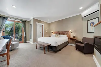 a large bedroom with a bed and two chairs at Hanford House in Sutter Creek