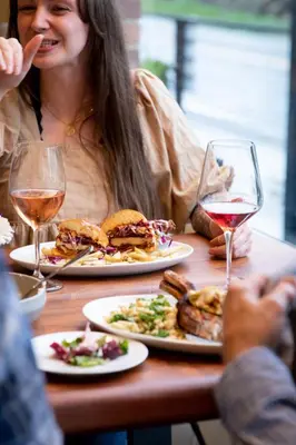 a woman sitting at a table with plates of food and wine at Hanford House in Sutter Creek