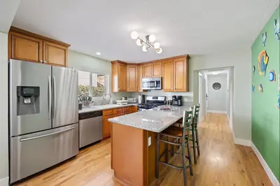a kitchen with stainless steel appliances and wooden cabinets at Cozy Home 7 minutes Walk to UC Davis Sacramento in Sacramento