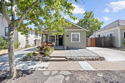 a house with a tree in front of a driveway at Cozy Home 7 minutes Walk to UC Davis Sacramento in Sacramento