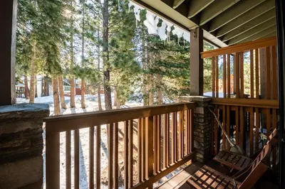 a wooden porch with a view of the woods at Lux Retreat, Covered Parking, Walk to Golf in Mammoth Lakes