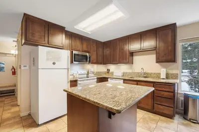 a kitchen with wooden cabinets and a white refrigerator at 3 Bedroom Kirkwood Condo – Base Camp condo in Kirkwood