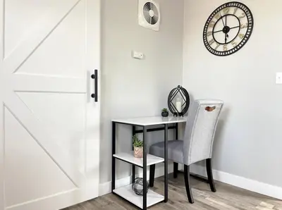a chair next to a table with a clock on a wall at Cozy Entire Home Gateway to Sequoia Pet Friendly in Visalia