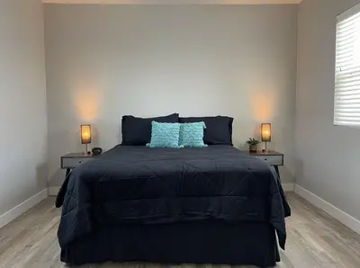 a bedroom with a bed with blue pillows and two lamps at Cozy Entire Home Gateway to Sequoia Pet Friendly in Visalia