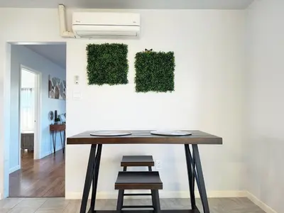 a table with a chair next to a wall with green plants at Sequoia Basecamp With Fenced Yard in Visalia