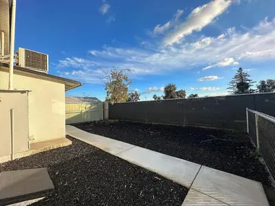 a backyard with a fence and a driveway at Sequoia Basecamp With Fenced Yard in Visalia