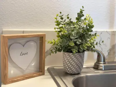 a picture and a vase with a heart on a sink at Sequoia Basecamp With Fenced Yard in Visalia