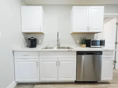 a white kitchen with a sink and a microwave at Ocean Breeze 2 bedroom w fenced yard on Mooney in Visalia