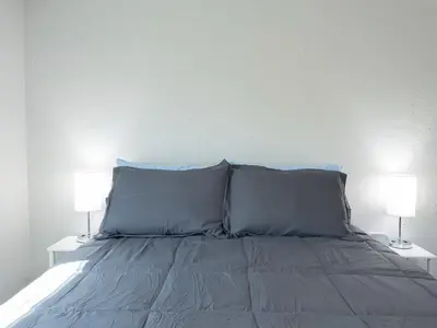 a bed with blue pillows and two lamps on tables at Ocean Breeze 2 bedroom w fenced yard on Mooney in Visalia