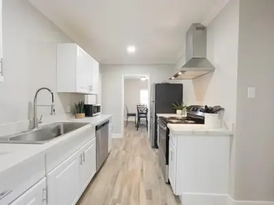 a white kitchen with a sink and a refrigerator at Ocean Breeze 2 bedroom w fenced yard on Mooney in Visalia