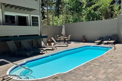 a swimming pool with chairs and a house at Sierra Megeve 13 in Mammoth Lakes