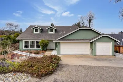 a green house with two white garage doors at Gorgeous 4BR Home Massive Modern Home in Cameron Park