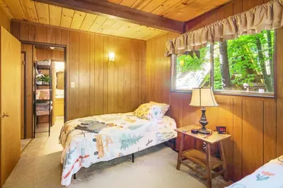 a bedroom with a bed and a table with a lamp at Walk to Fly-In Lake Blue Lake Springs Cabin! in Arnold