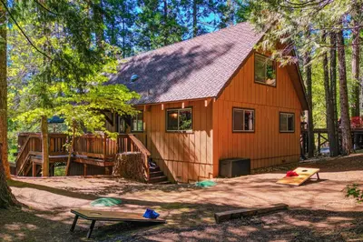 a red house with a playground in front of it at Walk to Fly-In Lake Blue Lake Springs Cabin! in Arnold