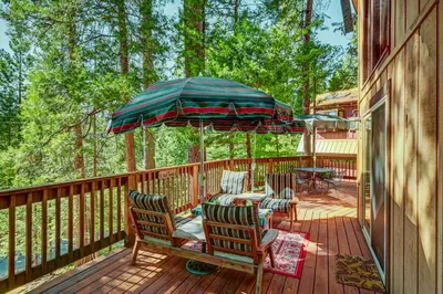 a deck with chairs and a table and an umbrella at Walk to Fly-In Lake Blue Lake Springs Cabin! in Arnold