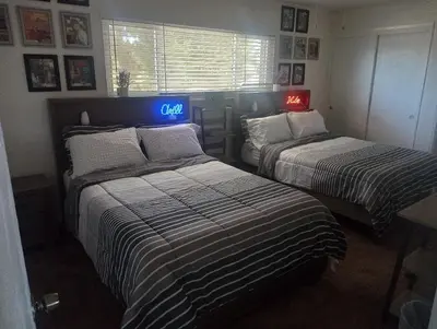 two beds in a room with a clock on the wall at Franklin Apt in Fresno