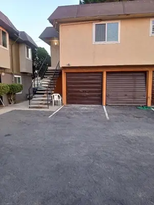 a house with two garage doors in a parking lot at Franklin Apt in Fresno