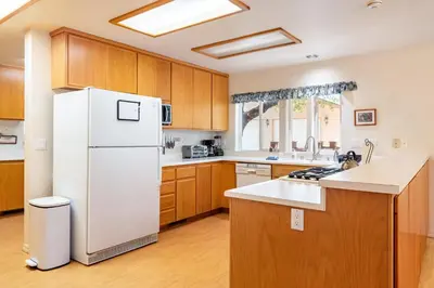 a kitchen with a white refrigerator and wooden cabinets at Groveland 2BR Home - Mountain Retreat in Groveland