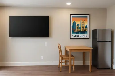 a room with a table and a television on a wall at Value Suites Extended Stay in Sacramento