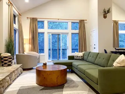 a living room with a green couch and a table at Enchanting Creekside Cabin Retreat near Yosemite National Park in California in Oakhurst