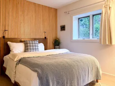 a bedroom with a large bed and a window at Enchanting Creekside Cabin Retreat near Yosemite National Park in California in Oakhurst