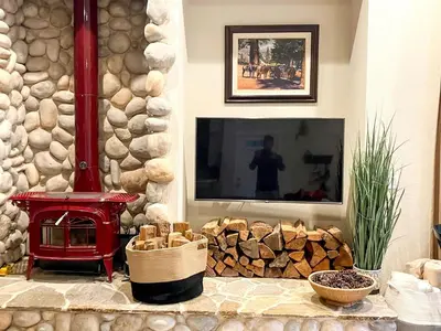 a living room with a fireplace and a television at Enchanting Creekside Cabin Retreat near Yosemite National Park in California in Oakhurst