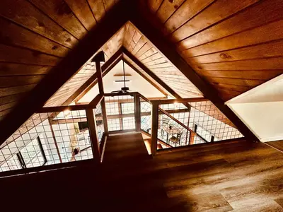 an attic room with a large window and a chandelier at The Falls-Overlooks a waterfall-BBQ-Sleeps 4 in Oakhurst